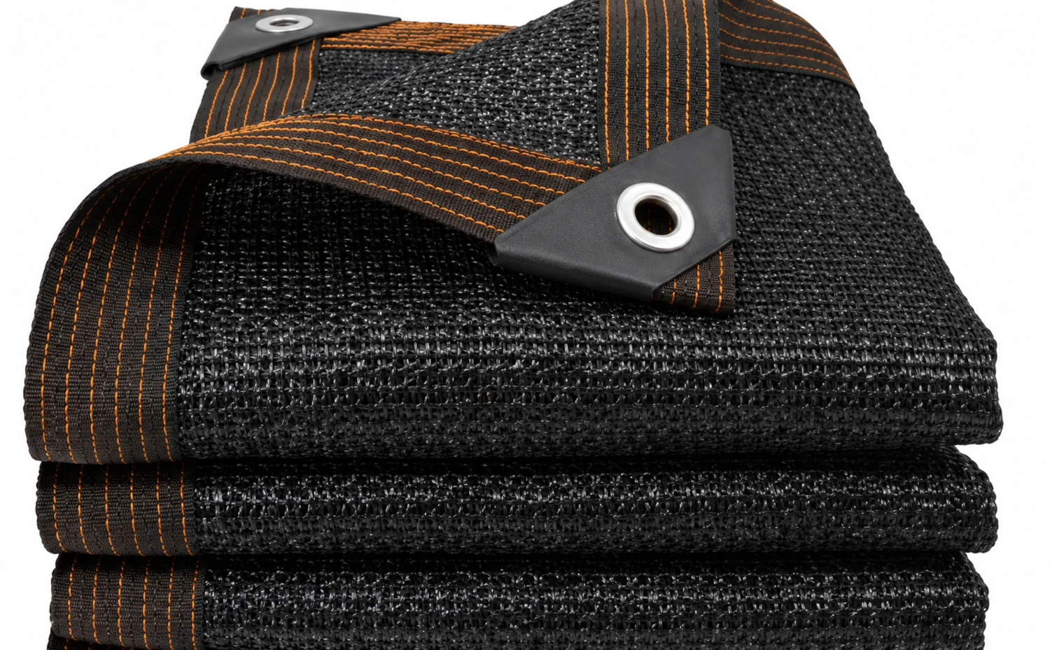 Folded black agricultural shade cloth with reinforced eyelets and orange edge stitching